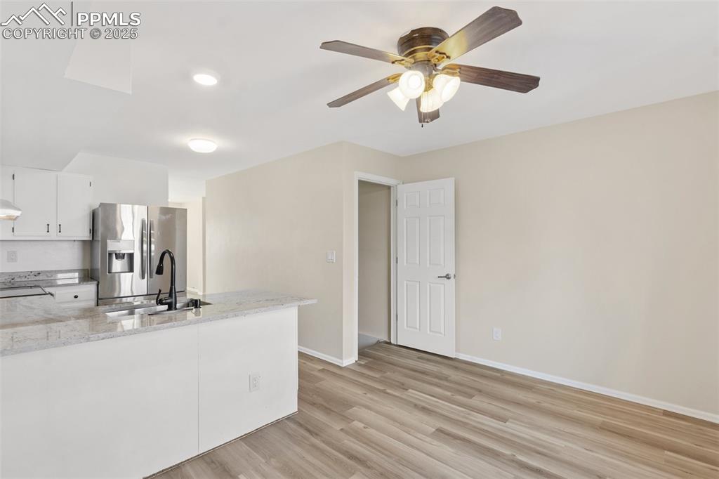 Image 8 of 26: Kitchen with light wood finished floors, stainless steel fridge with ice di