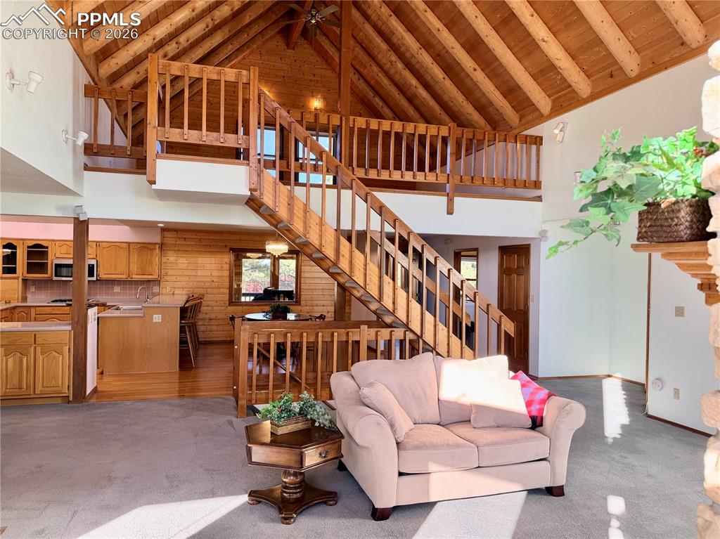 Image 14 of 45: Carpeted living room featuring a high wood beamed ceiling and a ceiling fan