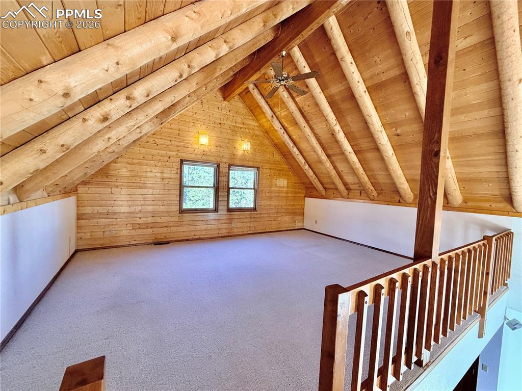 Image 15 of 45: Additional living space with carpet flooring, a wood ceiling with exposed b