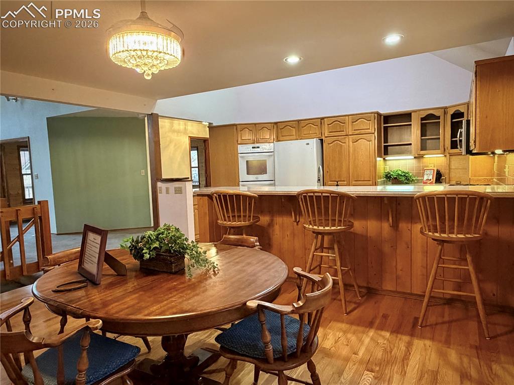 Image 17 of 45: Dining area with light wood finished floors, recessed lighting, and vaulted