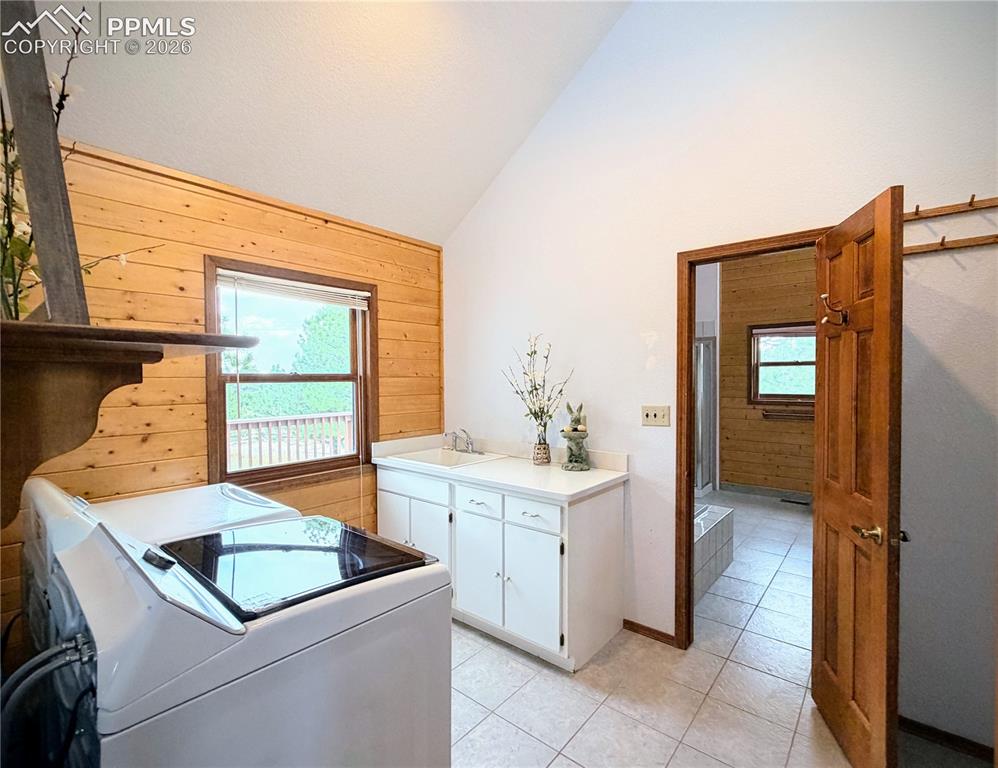 Image 24 of 45: Laundry room with wood walls, vaulted ceiling, independent washer and dryer