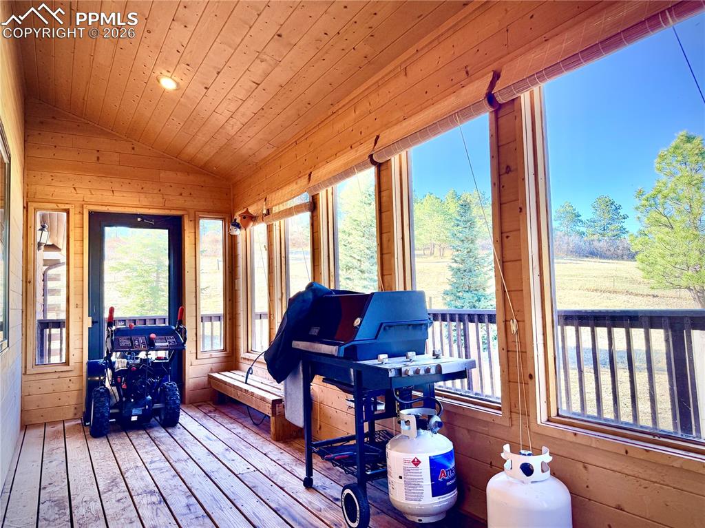 Image 27 of 45: Sunroom featuring wooden walls, a vaulted wood ceiling, hardwood / wood-sty