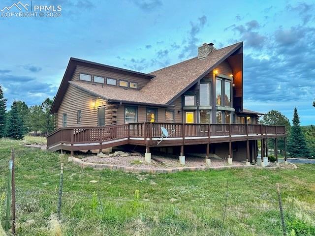 Image 4 of 45: Back of property with a wooden deck, a chimney, a shingled roof, a yard, an