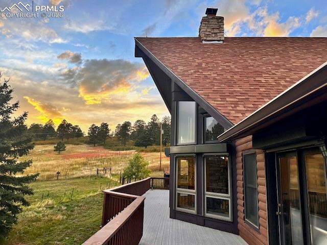 Image 5 of 45: View of side of property with a shingled roof, a chimney, and a composite d