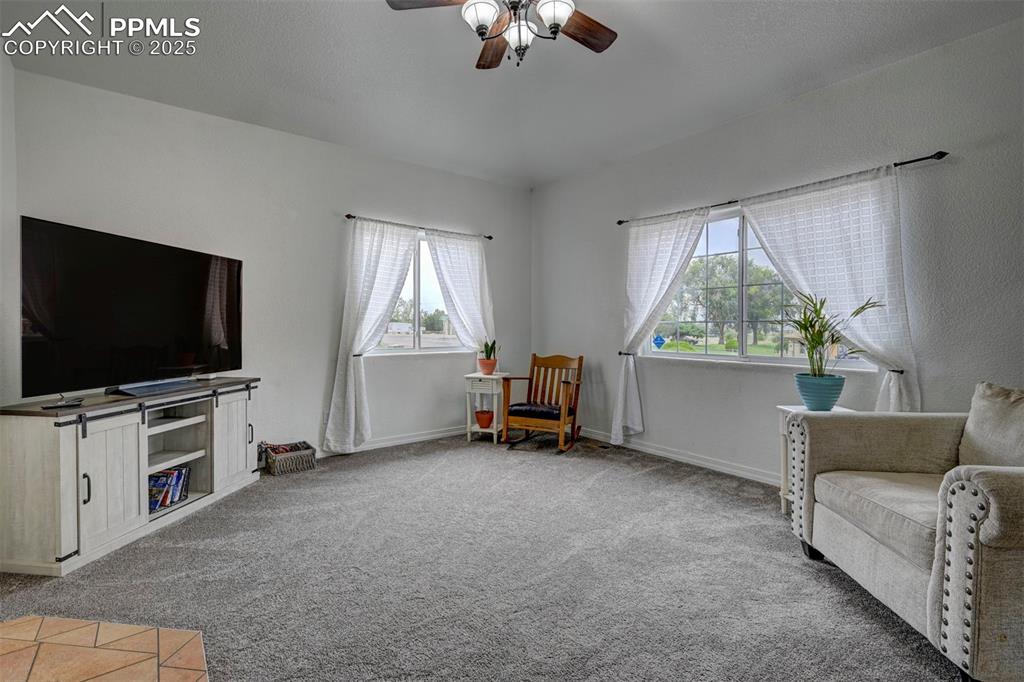 Image 12 of 47: Sitting room with light colored carpet and a ceiling fan