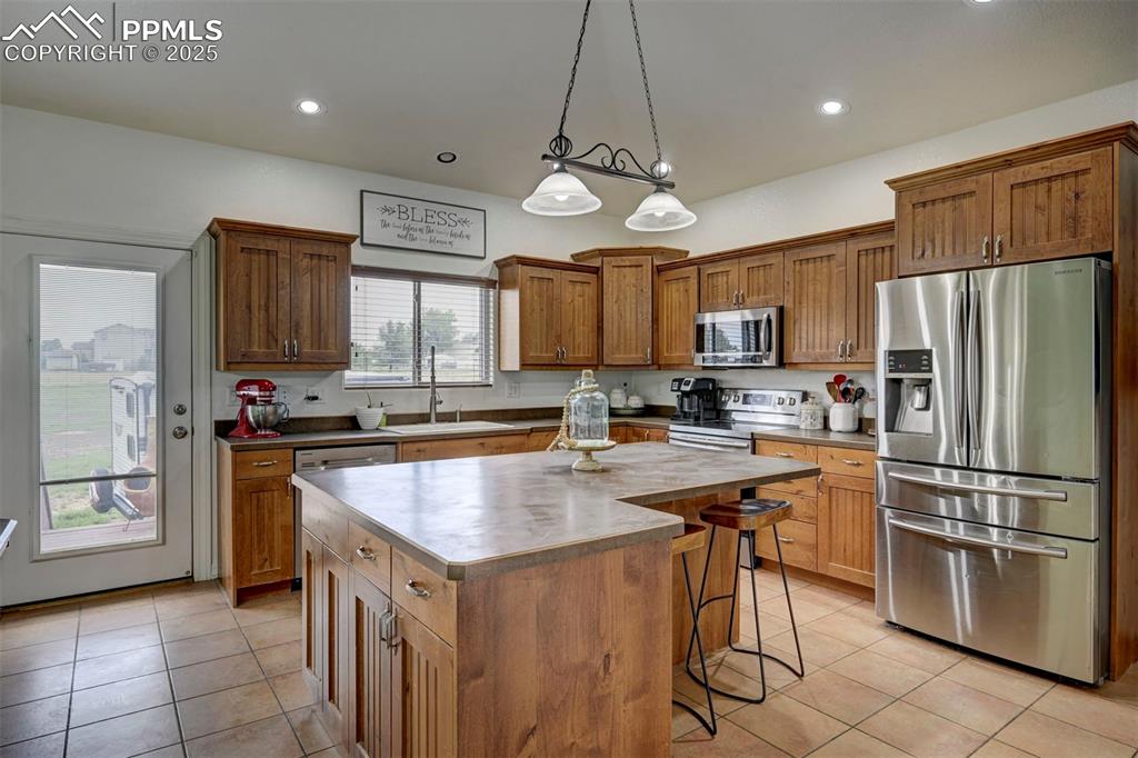 Image 17 of 47: Kitchen with appliances with stainless steel finishes, light tile patterned