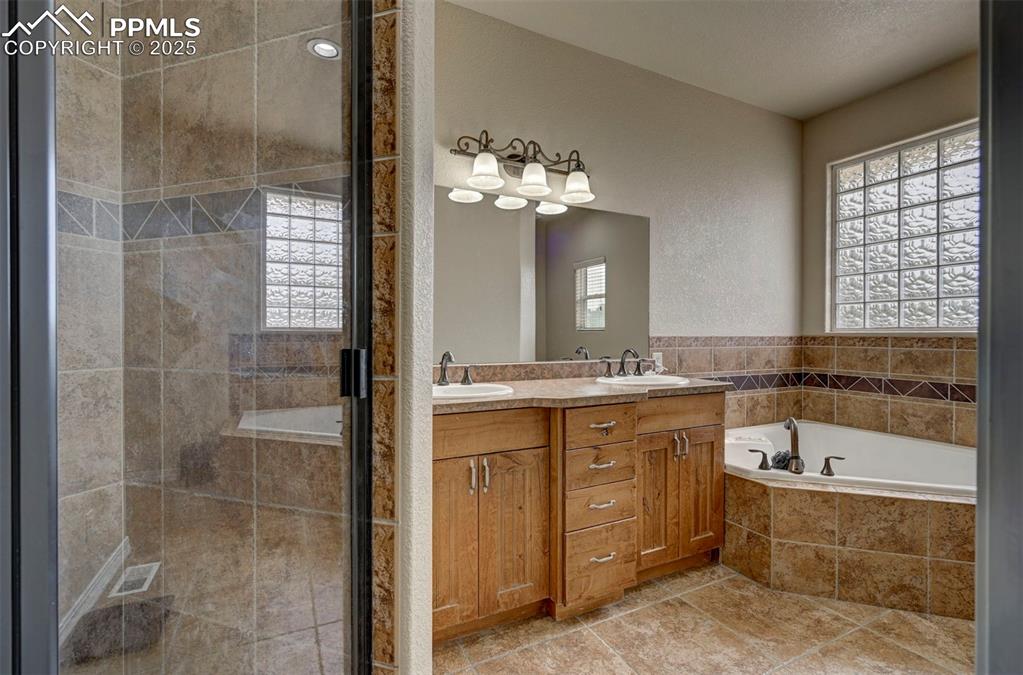 Image 23 of 47: Full bath with a stall shower, a garden tub, and healthy amount of natural 