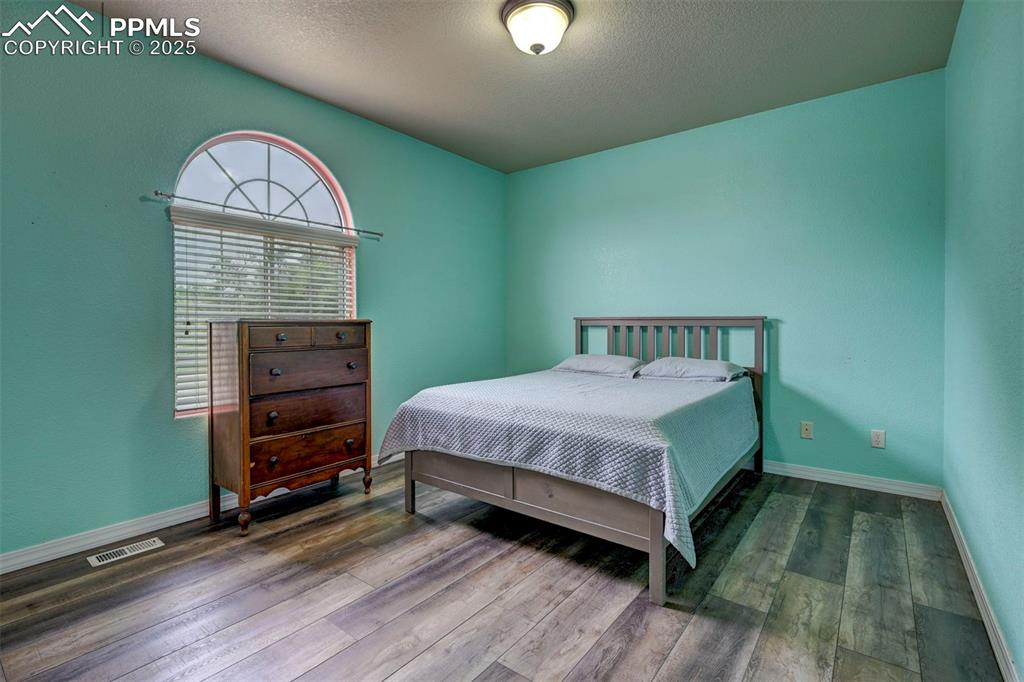 Image 27 of 47: Bedroom with wood finished floors and a textured ceiling