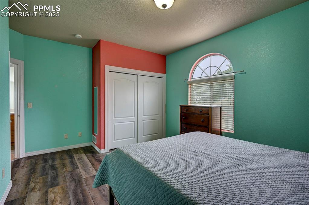 Image 28 of 47: Bedroom with dark wood-style flooring, a textured ceiling, and a closet