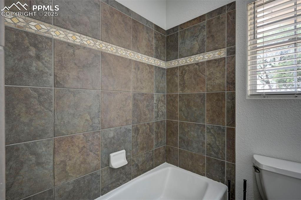 Image 32 of 47: Full bathroom with a textured wall and tub / shower combination