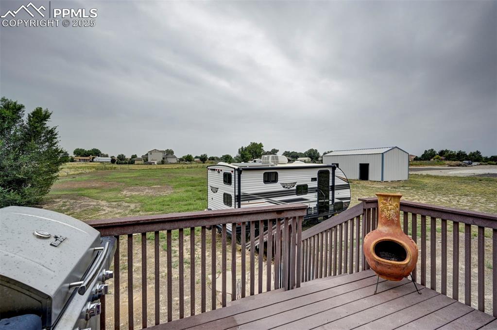 Image 39 of 47: Deck with a grill, an outdoor structure, and a lawn