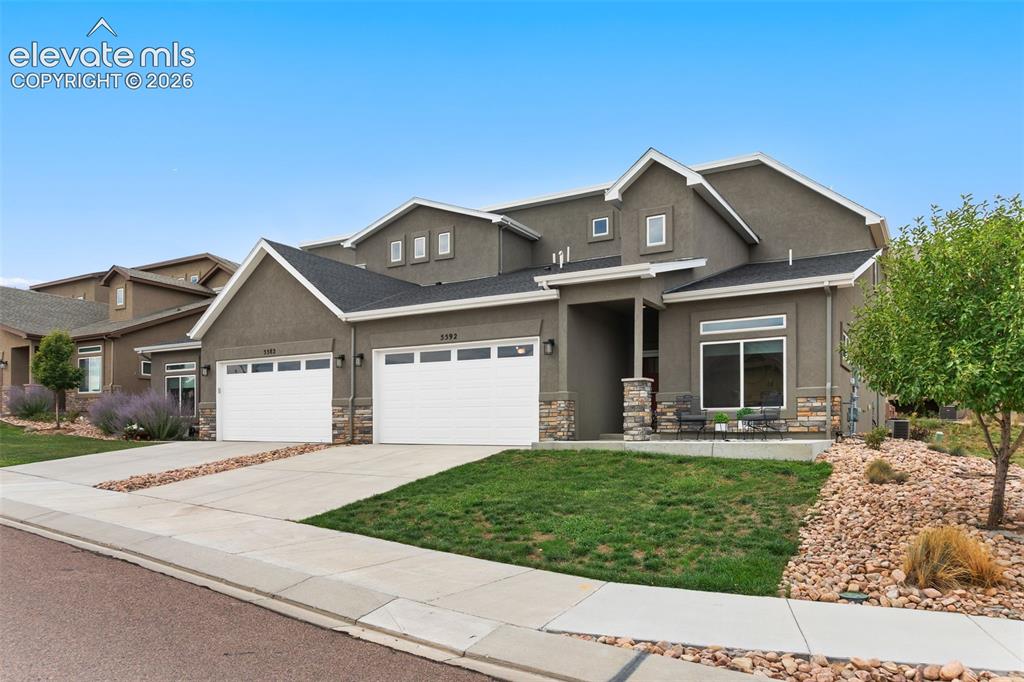 Image 1 of 43: Stucco exterior with stone accents, multiple garage doors, front entry porc