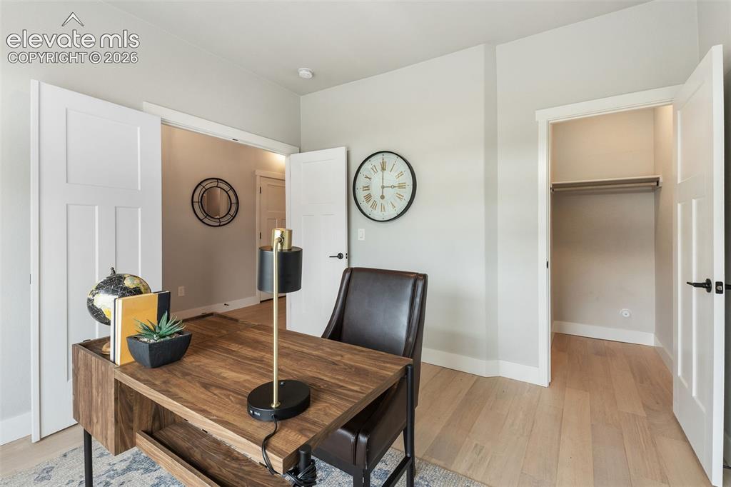 Image 14 of 43: Light wood-finish flooring, white paneled doors, and a closet with a hangin