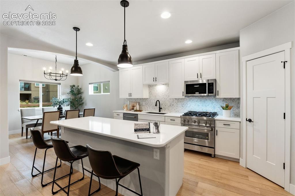 Image 18 of 43: Kitchen featuring a central island with countertop seating, white cabinetry