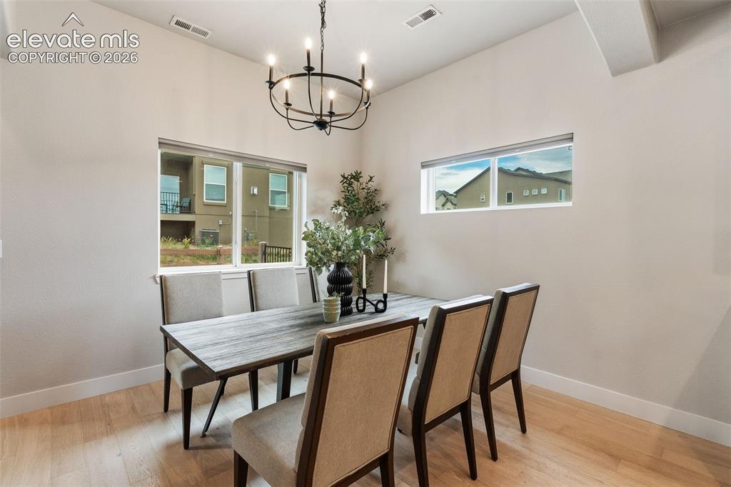 Image 21 of 43: Vaulted ceiling with an iron chandelier, wood-finish flooring, and multiple