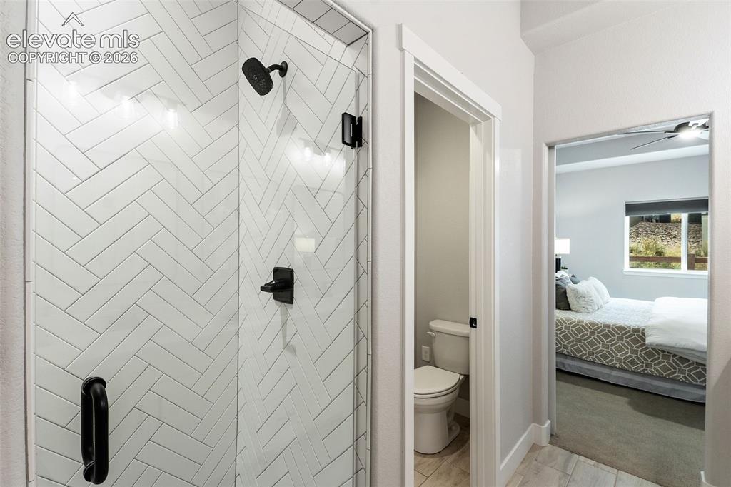 Image 29 of 43: Glass-enclosed shower with subway tile in a herringbone pattern, matte blac
