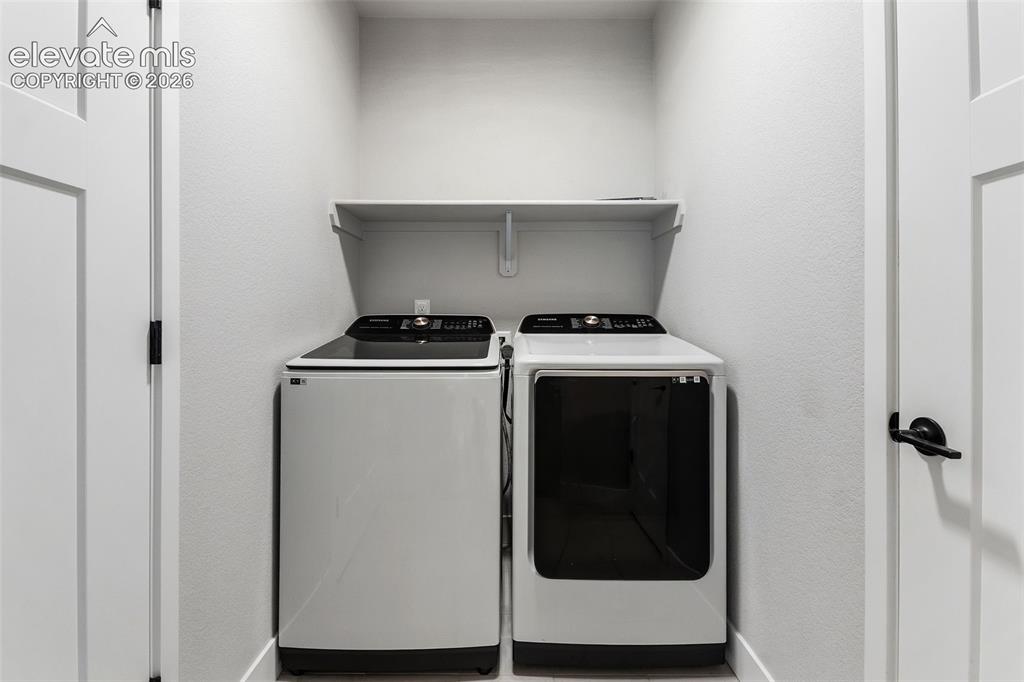 Image 30 of 43: Dedicated laundry area featuring a white built-in shelf and light gray wall