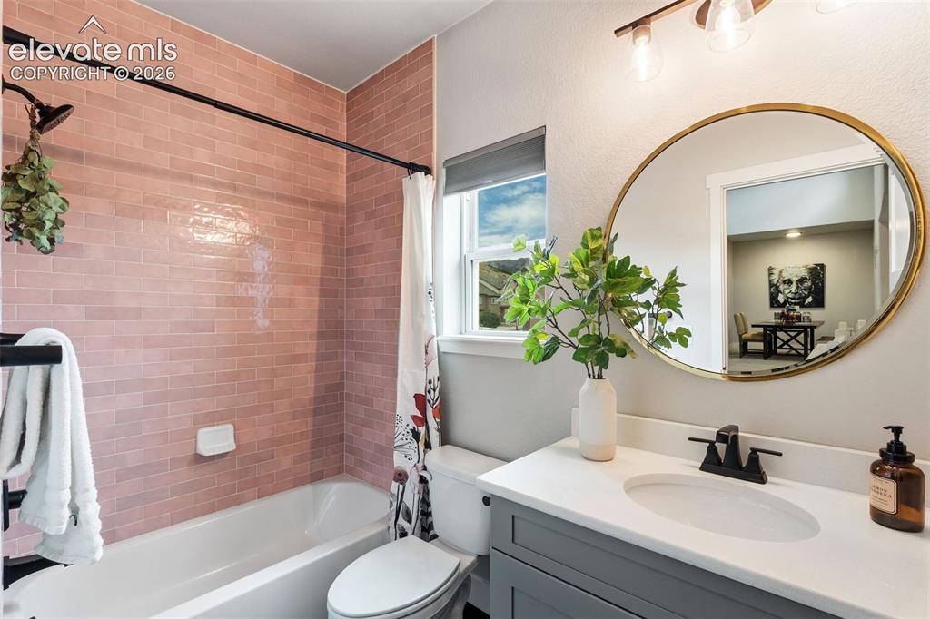 Image 37 of 43: Bathroom featuring a white bathtub, pink subway tile surround, white vanity