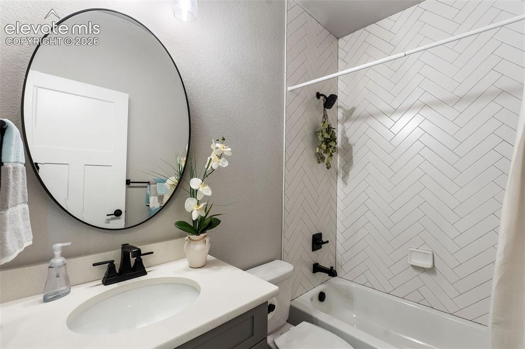Image 41 of 43: Vanity with an integrated sink and matte black faucet, framed round mirror,