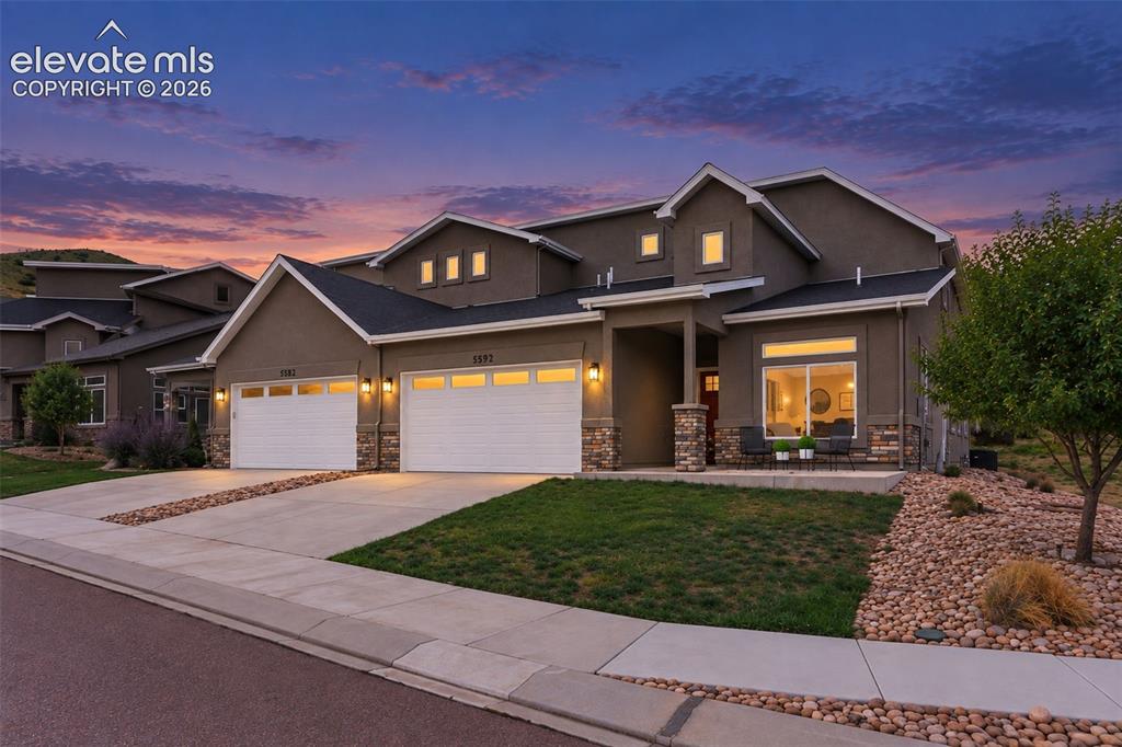 Image 5 of 43: Stucco exterior with stone accents, two-car garage, covered porch entry, an