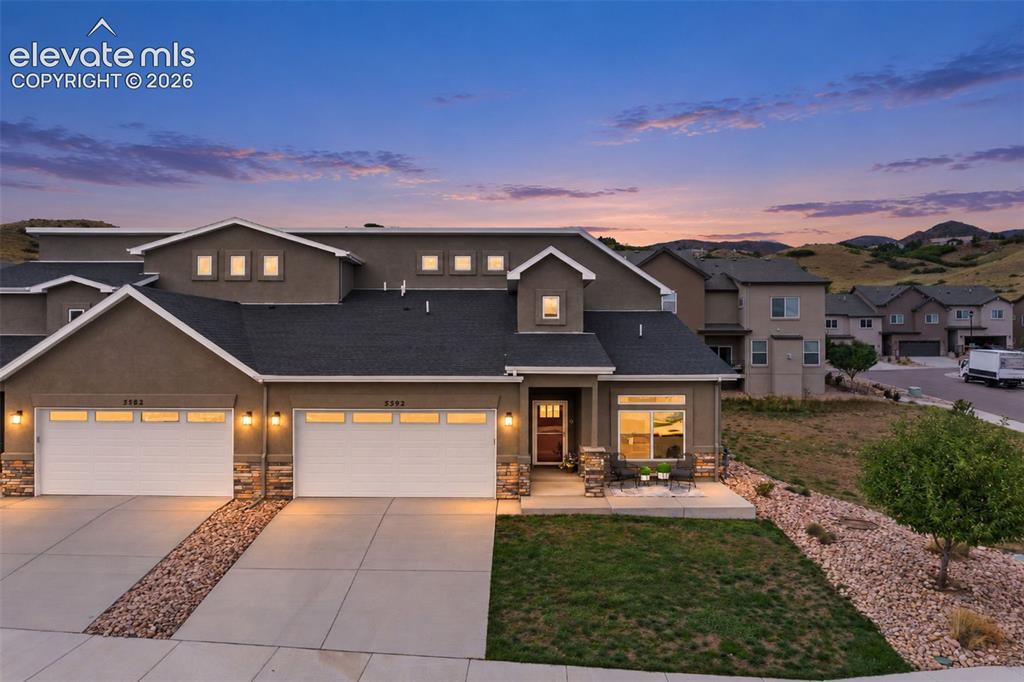 Image 9 of 43: Stucco exterior with stone accents, attached two-car garages, covered entry
