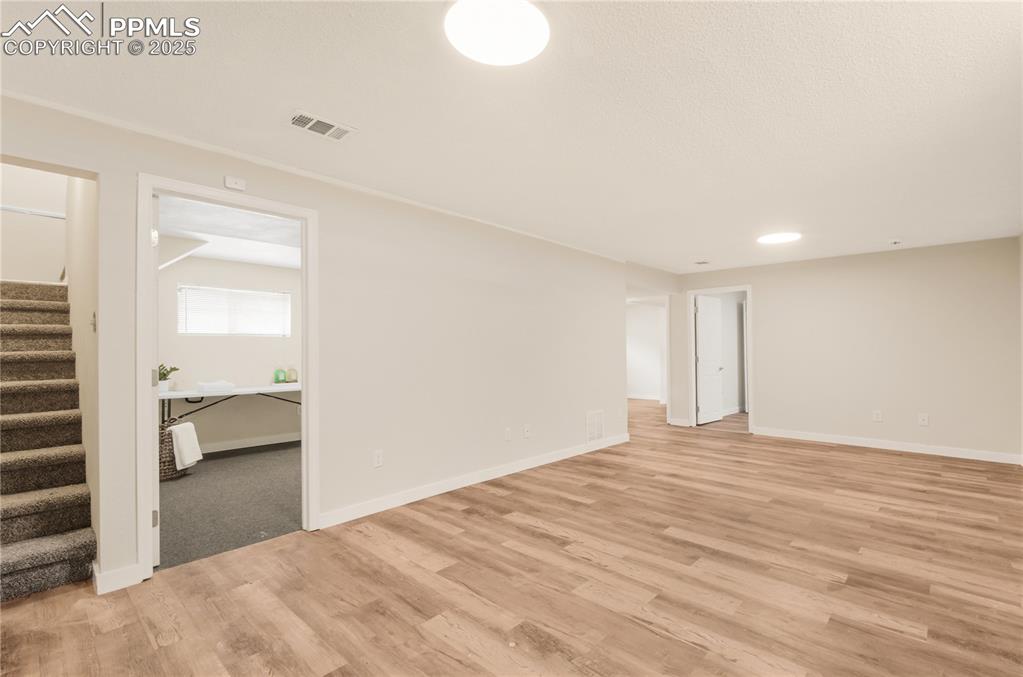 Image 14 of 25: Family room with stairs and light wood-style floors