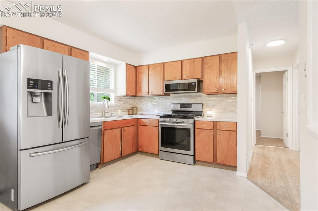Image 4 of 25: Kitchen featuring appliances with stainless steel finishes, light counterto