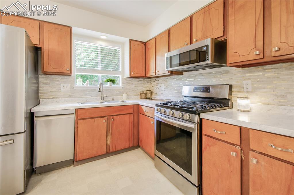 Image 5 of 25: Kitchen with stainless steel appliances, light floors, light countertops, d