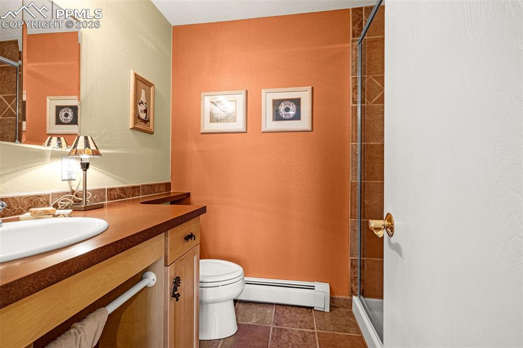 Image 10 of 42: Full bathroom, basement featuring vanity, baseboard heating, a stall shower