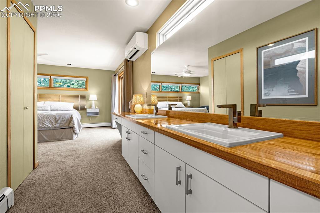 Image 14 of 42: Bathroom with ensuite bathroom, double vanity, light carpet, and a baseboar