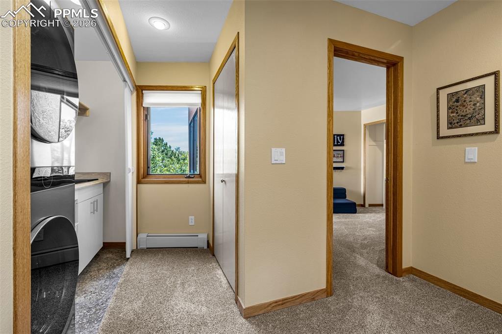 Image 18 of 42: Laundry area featuring baseboard heating, washer / dryer, and light carpet