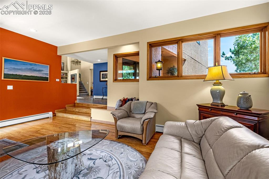 Image 32 of 42: Living room with wood finished floors and baseboard heating