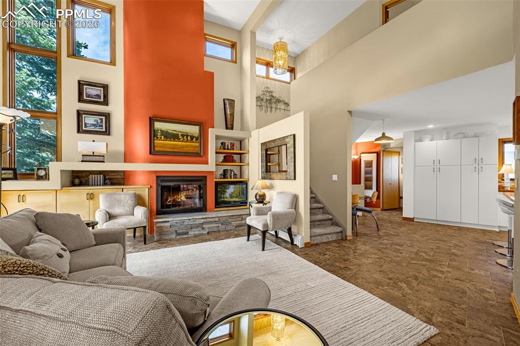 Image 34 of 42: Living room featuring a fireplace, a high ceiling, and a chandelier