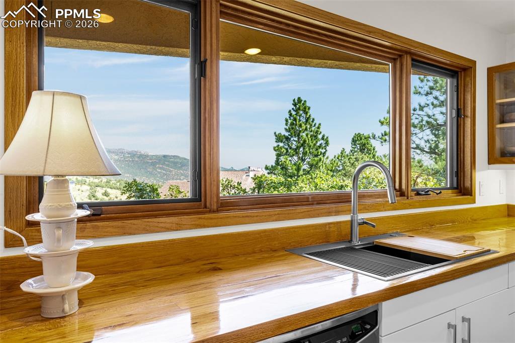 Image 38 of 42: Kitchen view of white cabinets, stainless steel dishwasher, and glass front