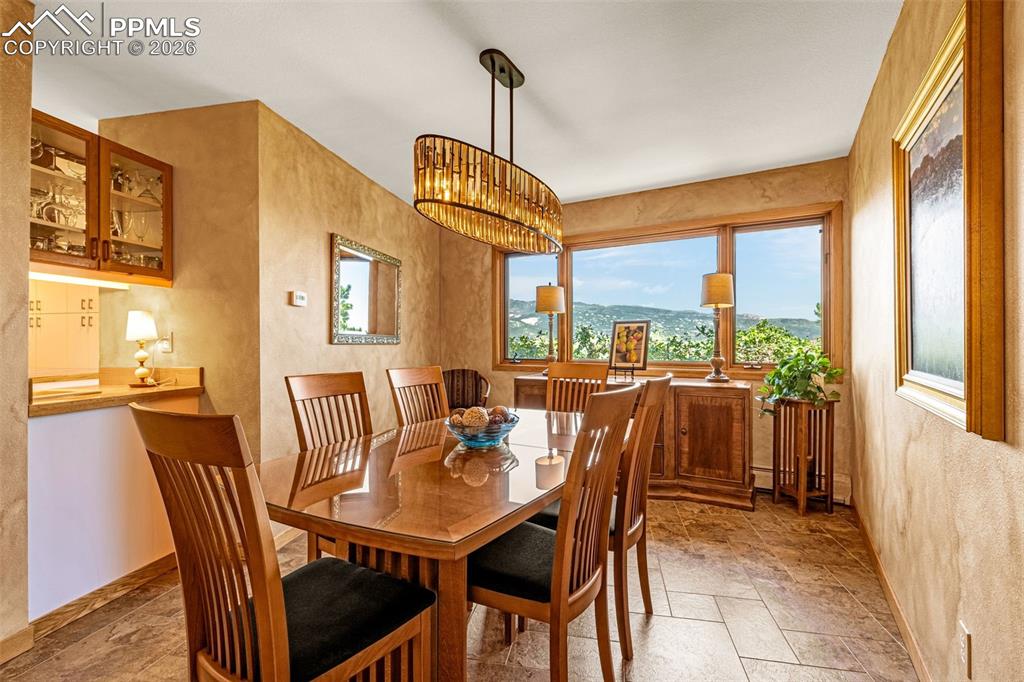 Image 39 of 42: Dining area featuring stone tile floors, a textured wall, and hanging light