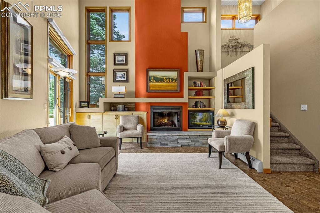 Image 4 of 42: Living area featuring a high ceiling and a stone fireplace