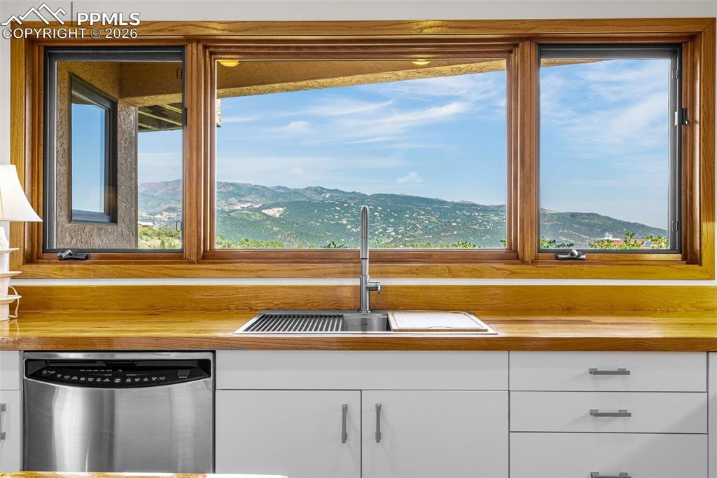 Image 6 of 42: Kitchen with stainless steel dishwasher, a mountain view, and white cabinet