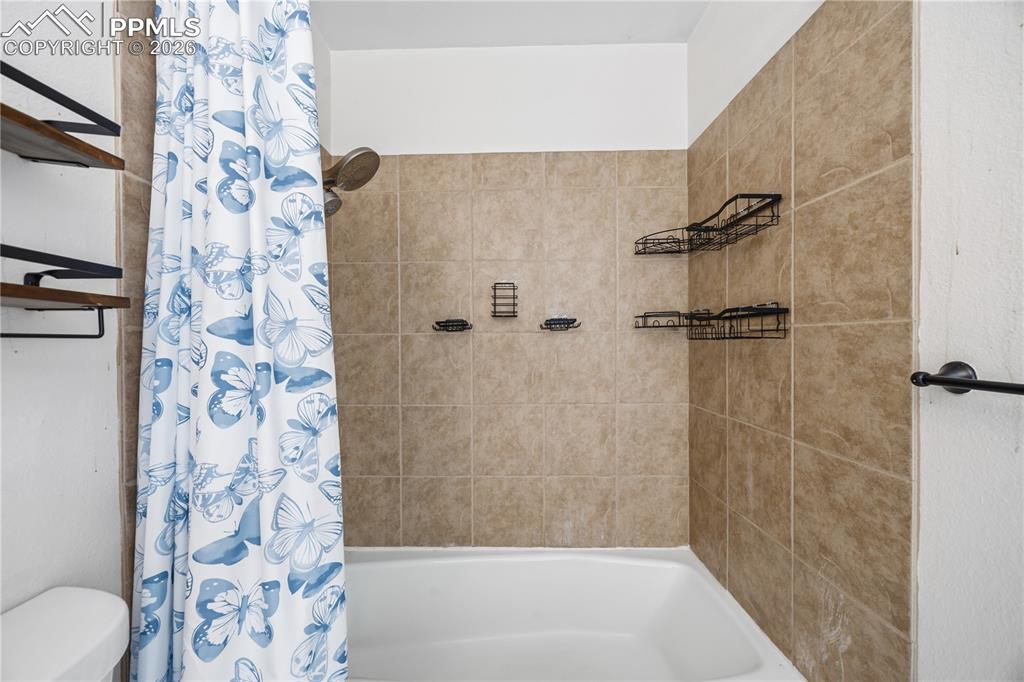 Image 18 of 27: Tiled tub/shower in the primary bathroom.