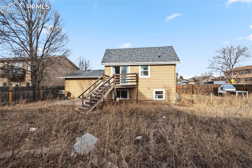 Image 26 of 27: The fenced backyard has a concrete patio, deck with stairs to the backyard,