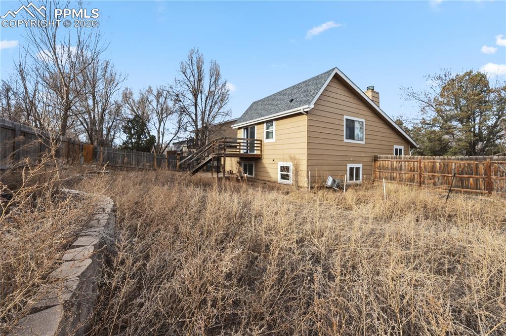 Image 27 of 27: Rear view of home and fenced backyard.