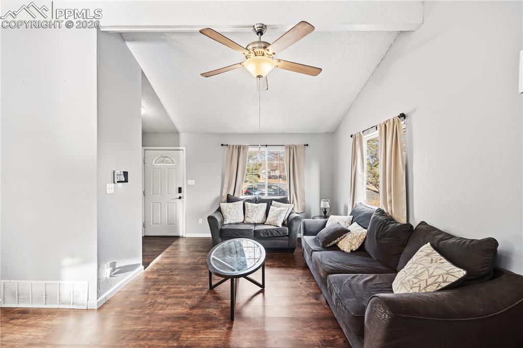 Image 5 of 27: The vaulted living room features LVP floors, a lighted ceiling fan, and vie