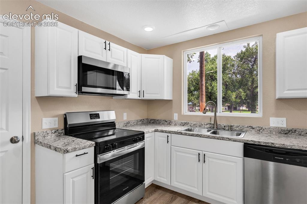 Image 17 of 50: White shaker-style cabinetry with matte black hardware, stainless steel app