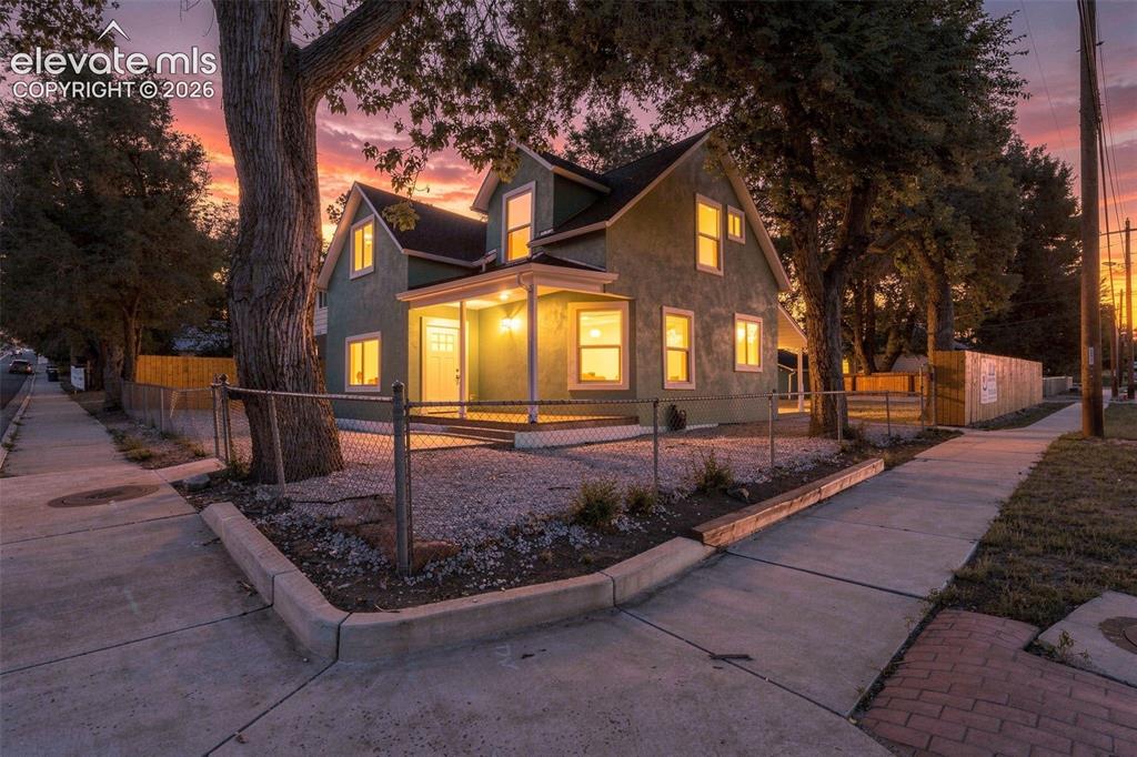 Image 2 of 50: Green exterior with white trim, front porch, dormer windows, and a chain li