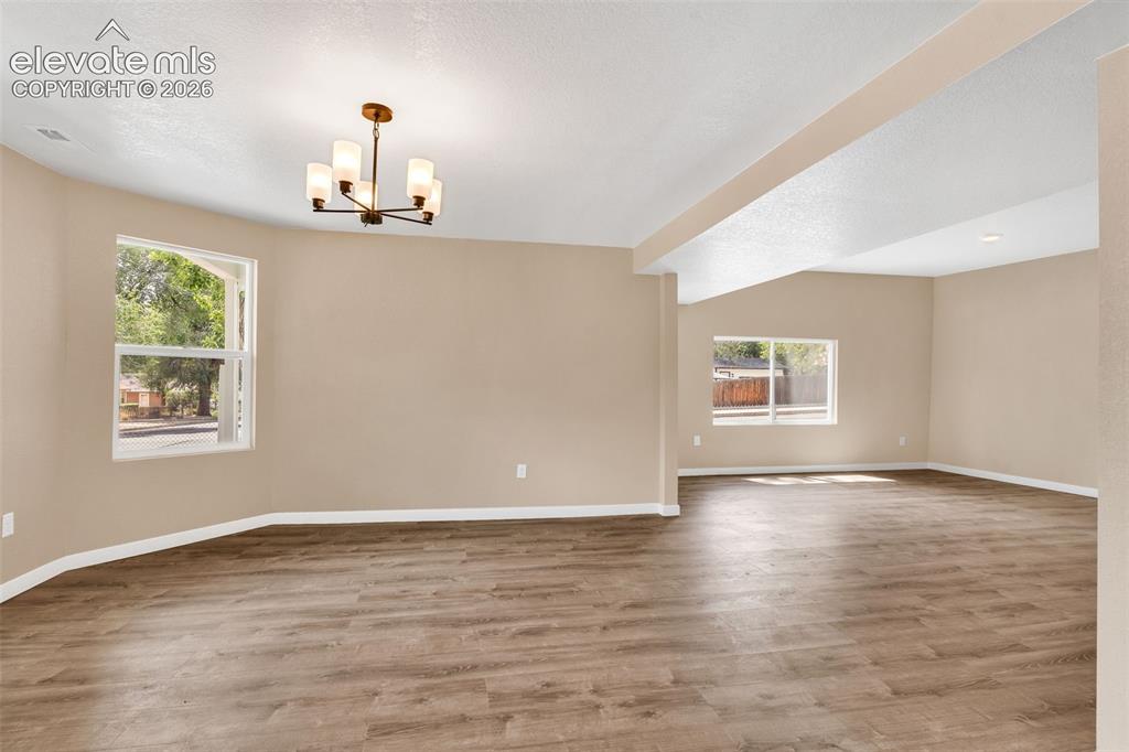 Image 21 of 50: Spacious interior with wood-finish flooring, multiple windows, and a bronze
