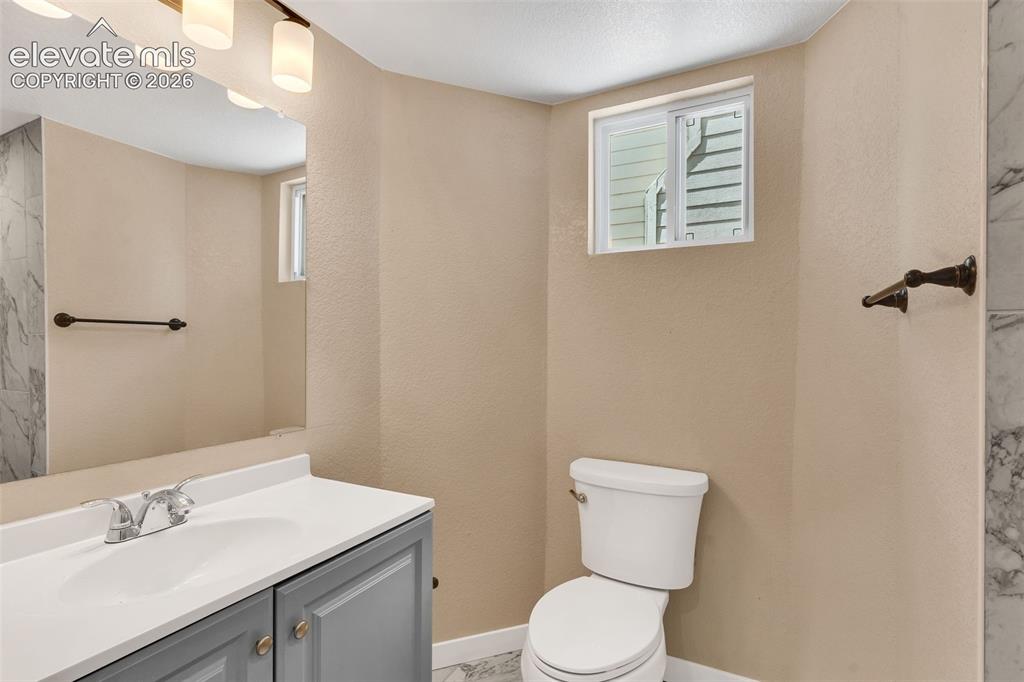 Image 26 of 50: Vanity with a white countertop and chrome faucet, large wall mirror, and mo