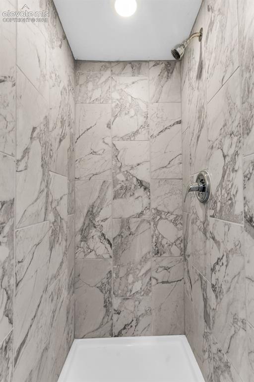 Image 27 of 50: Shower enclosure featuring full-height tile walls with a marble-look finish