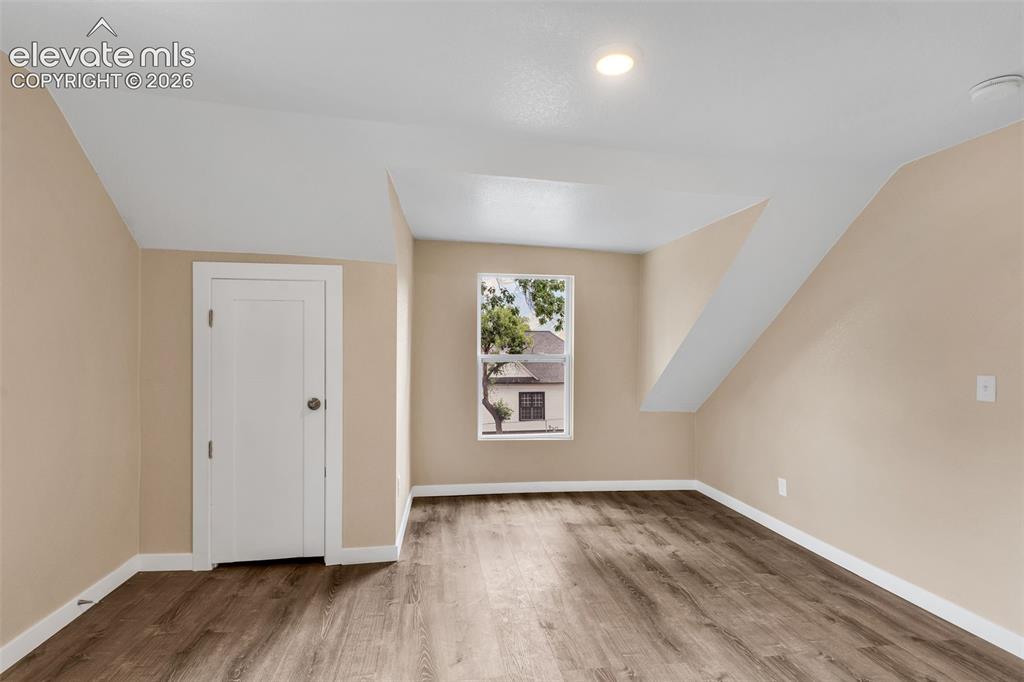 Image 29 of 50: Wood-finish flooring, recessed lighting, and a white interior door