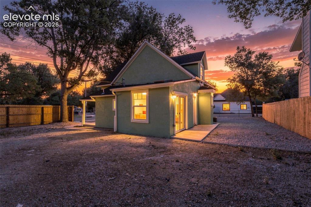 Image 3 of 50: Stucco exterior residence with a gabled roofline, concrete patio, and a gra