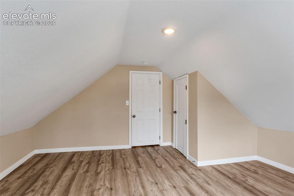 Image 34 of 50: Wood-finish flooring with white trim, neutral wall paint, white doors, and