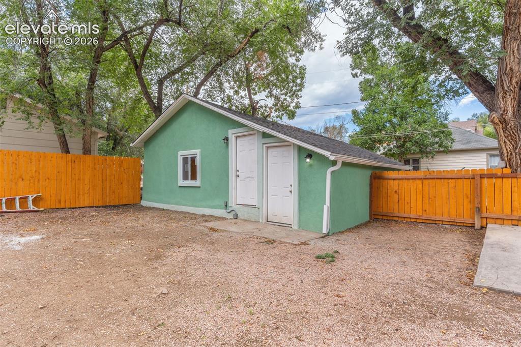 Image 47 of 50: Detached structure with stucco exterior, dual entry doors, and a single win